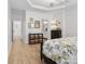 Bright main bedroom showcasing wood floors, tray ceiling, a storage chest, and a ensuite bathroom at 4022 Carl Parmer Dr, Harrisburg, NC 28075