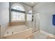 Bright bathroom with a soaking tub, glass-enclosed shower, and a large arched window at 4103 Belle Meade Cir, Belmont, NC 28012