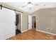Bright bedroom featuring wood-look floors, a ceiling fan, and an en suite bathroom with sliding barn door at 605 Gable Dr, Rock Hill, SC 29732
