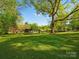 Beautiful backyard with green grass, shade trees, trampoline and gazebo in the distance at 6349 Lebanon Rd, Mint Hill, NC 28227