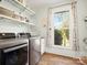 Well-lit laundry room featuring modern stainless steel washer, dryer, shelving and a window at 6349 Lebanon Rd, Mint Hill, NC 28227