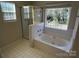 Well-lit bathroom featuring a soaking tub with window view and a glass-enclosed shower at 6827 Neuhoff Ln, Charlotte, NC 28269