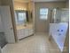 Bright bathroom featuring a double sink vanity, soaking tub, tiled floors, and natural light from the window at 6827 Neuhoff Ln, Charlotte, NC 28269