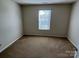 Cozy bedroom featuring neutral walls, carpeted floors, and a window providing natural light at 6827 Neuhoff Ln, Charlotte, NC 28269