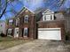 Traditional two-story brick home with attached two-car garage and well-maintained front yard at 6827 Neuhoff Ln, Charlotte, NC 28269