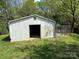 Exterior view of a white, metal backyard shed with an open doorway at 7939 Holly Hill Rd, Charlotte, NC 28227