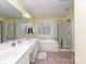 Bright bathroom with a double sink vanity, soaking tub, and glass shower at 8111 Sealey Ct, Charlotte, NC 28277