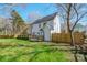 Backyard view of a two-story white home with a wooden deck, fenced in yard, and lush green grass at 8733 Canter Post Dr, Charlotte, NC 28216