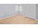 Empty bedroom with light gray walls, light wood flooring, two windows, and a closet at 8733 Canter Post Dr, Charlotte, NC 28216