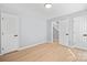 Empty room with light gray walls, light wood flooring, and three white doors at 8733 Canter Post Dr, Charlotte, NC 28216