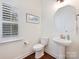 Well-lit half-bathroom with pedestal sink, octagonal mirror, and plantation shutters at 10521 Ardley Manor Dr, Mint Hill, NC 28227