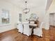 Dining room with hardwood floors, white chairs, modern light fixture, and natural light at 10521 Ardley Manor Dr, Mint Hill, NC 28227