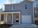 Close up of a charming two-story home featuring gray siding, a welcoming front porch, and an attached garage at 112 Brook Creek Dr, Troutman, NC 28166