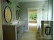 Bathroom with double sink vanity, tile floor, shower, and bright natural light at 1202 Louise Ln, Albemarle, NC 28001