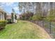 Large backyard with lush green grass and mature landscaping, partially enclosed by a black fence at 125 Whiterock Dr, Mount Holly, NC 28120