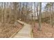 Scenic view of a wooden boardwalk winding through a wooded area with fall foliage at 125 Whiterock Dr, Mount Holly, NC 28120