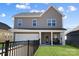 Two story home features a two car garage, black fence, and a cozy covered porch at 136 Kingston Dr, Locust, NC 28097