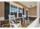 Inviting front porch featuring cozy rocking chairs, stone accents, and a welcoming entrance at 136 Kingston Dr, Locust, NC 28097