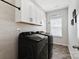 This laundry room features black front load machines, wooden cabinets, a drying rack, and a window for natural light at 136 Kingston Dr, Locust, NC 28097
