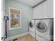 The laundry room has a front-load washer and dryer, with storage cabinets above, a window, and a vacuum cleaner at 170 Anniston Way, Davidson, NC 28036
