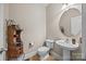 This powder room includes a pedestal sink, toilet, decorative shelf, and a round mirror with updated fixtures at 170 Anniston Way, Davidson, NC 28036