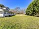 Large well-maintained backyard with mature trees and a home with a patio on a bright, sunny day at 214 W Elm St, Wingate, NC 28174