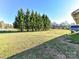 Expansive backyard featuring a line of tall evergreen trees, a sprawling grass area and distant structure at 214 W Elm St, Wingate, NC 28174