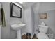 Charming powder room featuring a pedestal sink, framed mirror, and white toilet against a gray wall at 224 Mills Ln, Fort Mill, SC 29708