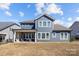 Backyard view features a two-story home with a covered patio, stone fireplace, and a well-maintained lawn at 2419 Paddlers Cove Dr, Clover, SC 29710