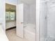 Bright bathroom featuring a tiled shower and tub, accessible from the bedroom at 2627 Bridgeville Ln, Charlotte, NC 28262