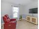 Cozy living room with a large red leather recliner, TV, cabinet, light-filled window and tile flooring at 2627 Bridgeville Ln, Charlotte, NC 28262