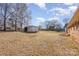 Backyard featuring a large grassy area with mature trees and a storage shed at 437 Valley St, Stanley, NC 28164