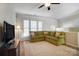 Bright living room with a plush green sectional sofa, ceiling fan, and large windows at 582 Sixth Baxter Xing, Fort Mill, SC 29708