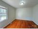 Sunlit bedroom showcasing hardwood floors, a large window, and neutral wall color at 7515 Riding Trail Rd, Charlotte, NC 28212