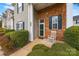 Cozy front porch with brick accent, a white rocking chair, and lush green bushes surrounding the entrance at 8830 Cinnabay Dr, Charlotte, NC 28216