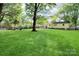 Expansive backyard with lush green lawn, mature trees, and outdoor seating area at 908 Dogwood Dr, Gastonia, NC 28054