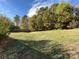 Large, grassy backyard with mature trees and a wooden privacy fence at 9513 Isaac Hunter Dr, Charlotte, NC 28214