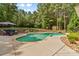 Beautiful backyard featuring an in-ground pool surrounded by lush landscaping, mature trees, and a cozy patio area with outdoor seating at 133 Crooked Branch Way, Troutman, NC 28166