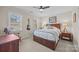 Well-lit bedroom features neutral walls, ceiling fan, and a queen bed with wooden frame and storage drawers at 13717 Strathaven Dr, Matthews, NC 28105