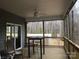 Spacious enclosed porch with ceiling fan, barstool seating, and views of the surrounding wooded area at 194 Hattaway Cir, Mount Gilead, NC 27306