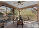 The screened porch with a ceiling fan and dining table, surrounded by lush greenery at 2924 Chelsea Dr, Charlotte, NC 28209