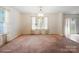 A dining room showcasing neutral walls, carpet flooring, and a hanging light fixture with natural light from the windows at 3627 Alexander Forest Dr, Charlotte, NC 28269