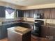Well-lit kitchen features dark cabinetry, laminate countertops, and modern appliances at 3627 Alexander Forest Dr, Charlotte, NC 28269