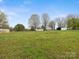 Large grassy field containing a house, sheds, and a trailer or shipping container in the distance at 5622 S Rocky River Rd, Monroe, NC 28112