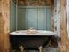 Close up of a claw foot bathtub with wood accents, and hexagon tile flooring at 5622 S Rocky River Rd, Monroe, NC 28112