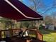 Inviting back deck with a retractable awning, overlooking a well-maintained lawn and landscape at 7700 Sedgebrook E Dr, Stanley, NC 28164