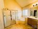 Bathroom featuring a glass-enclosed shower, soaking tub, vanity, and large window at 7700 Sedgebrook E Dr, Stanley, NC 28164