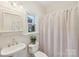 Clean bathroom with a pedestal sink, toilet, and shower with neutral curtain providing a functional, tidy space at 820 Hampshire Hill Rd # 106, Matthews, NC 28105