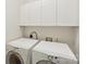 Efficient laundry area with white washer and dryer units, complemented by above storage cabinets for organized utility at 820 Hampshire Hill Rd # 106, Matthews, NC 28105