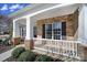 Inviting front porch featuring stone accents, white columns, and neat landscaping details at 9332 Whistling Straits Dr, Fort Mill, SC 29707